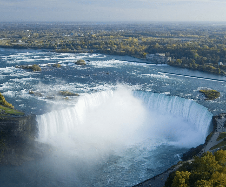Aerial view of Niagara Falls with surrounding landscape, showcasing the majestic site on the Canada visit visa.