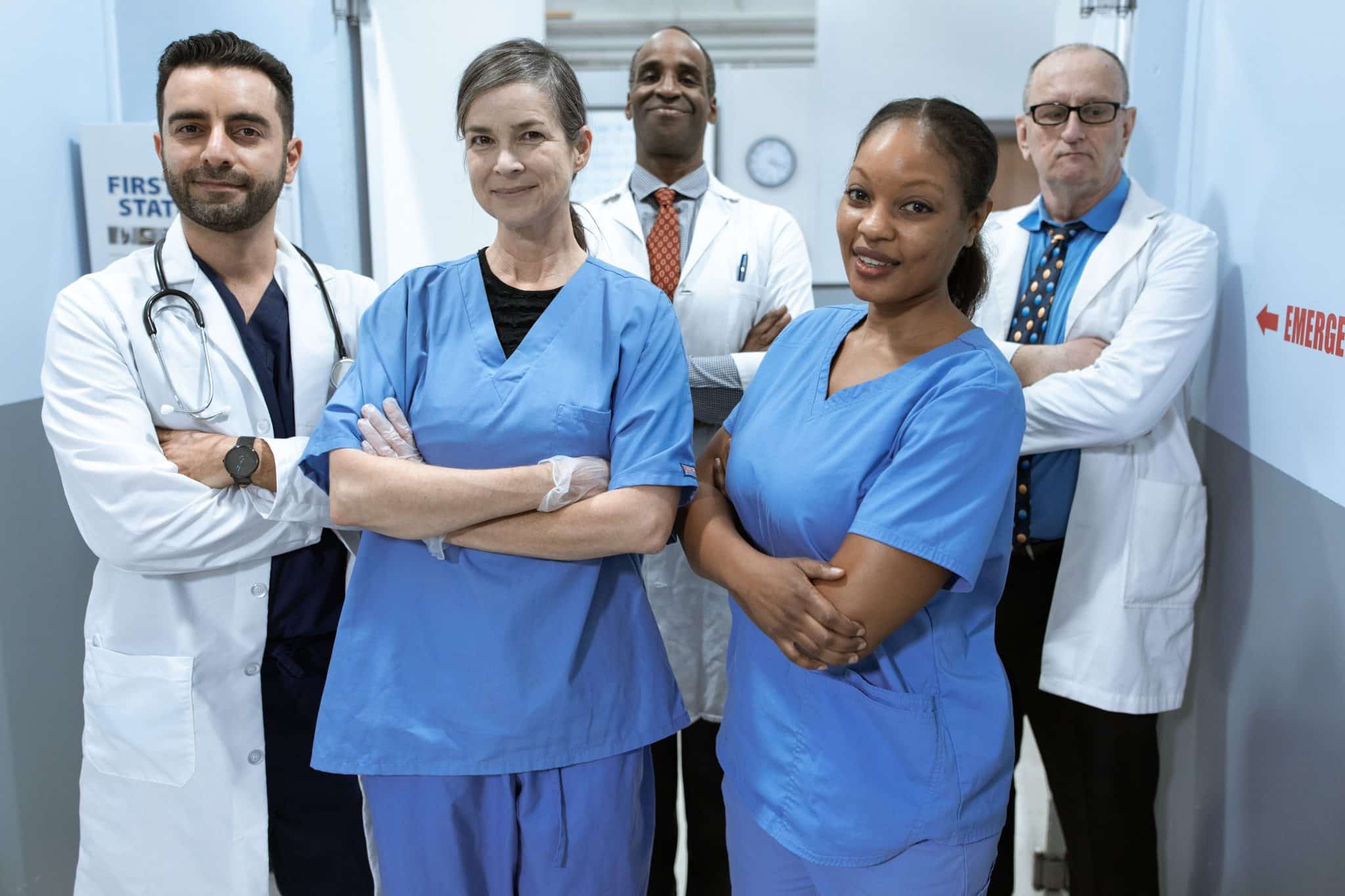 A diverse group of medical professionals, including Canada work permit holders, standing confidently in an emergency room environment.