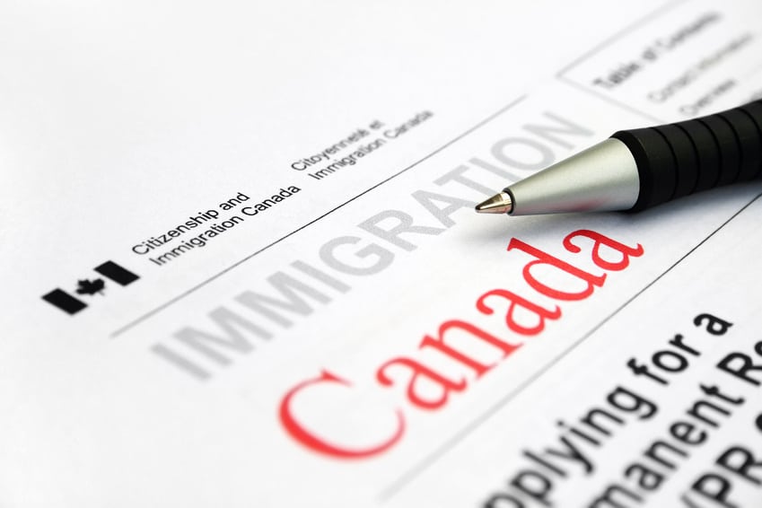 A pen resting on a Canada immigration application form.